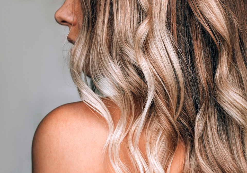 Luminous, wavy hair showing a harmonious blend of blonde highlights and lowlights for natural depth and dimension.