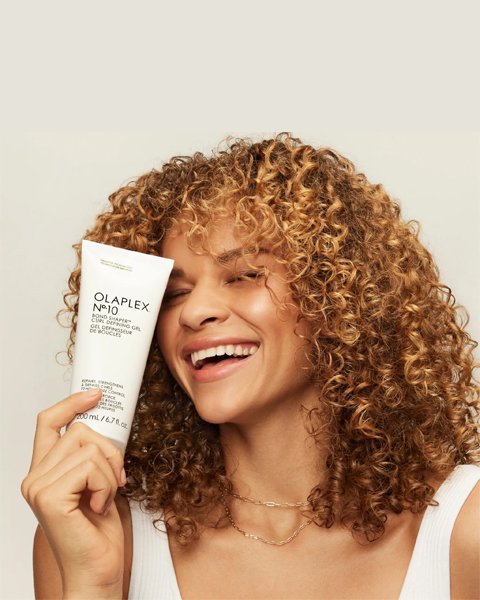 Woman with defined, frizz-free natural curls after an Artysto Olaplex Curl Treatment, showcasing the bond-building technology.