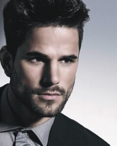 Headshot of a confident man with a stylish haircut and precise beard trim, representing the Urban Man comprehensive grooming experience.