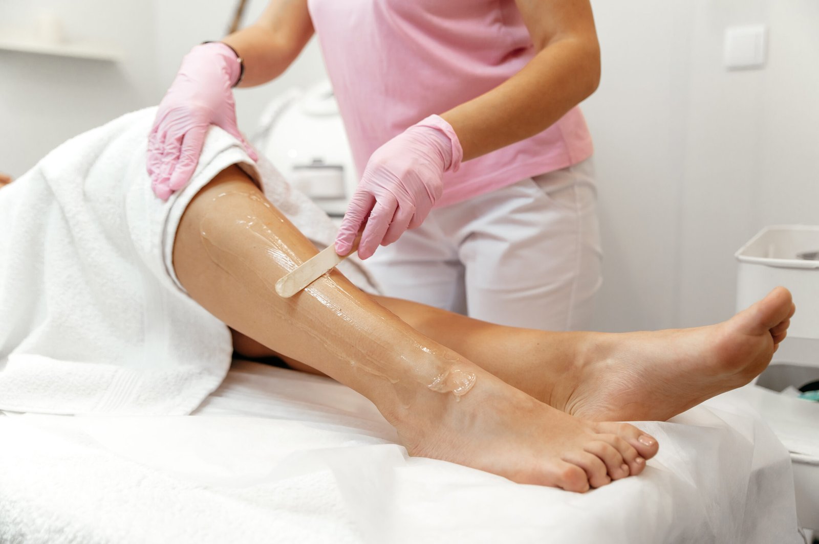 Professional technician preparing a client's leg with pre-waxing gel/oil for the Full Legs Waxing service, ensuring smooth, sleek results.