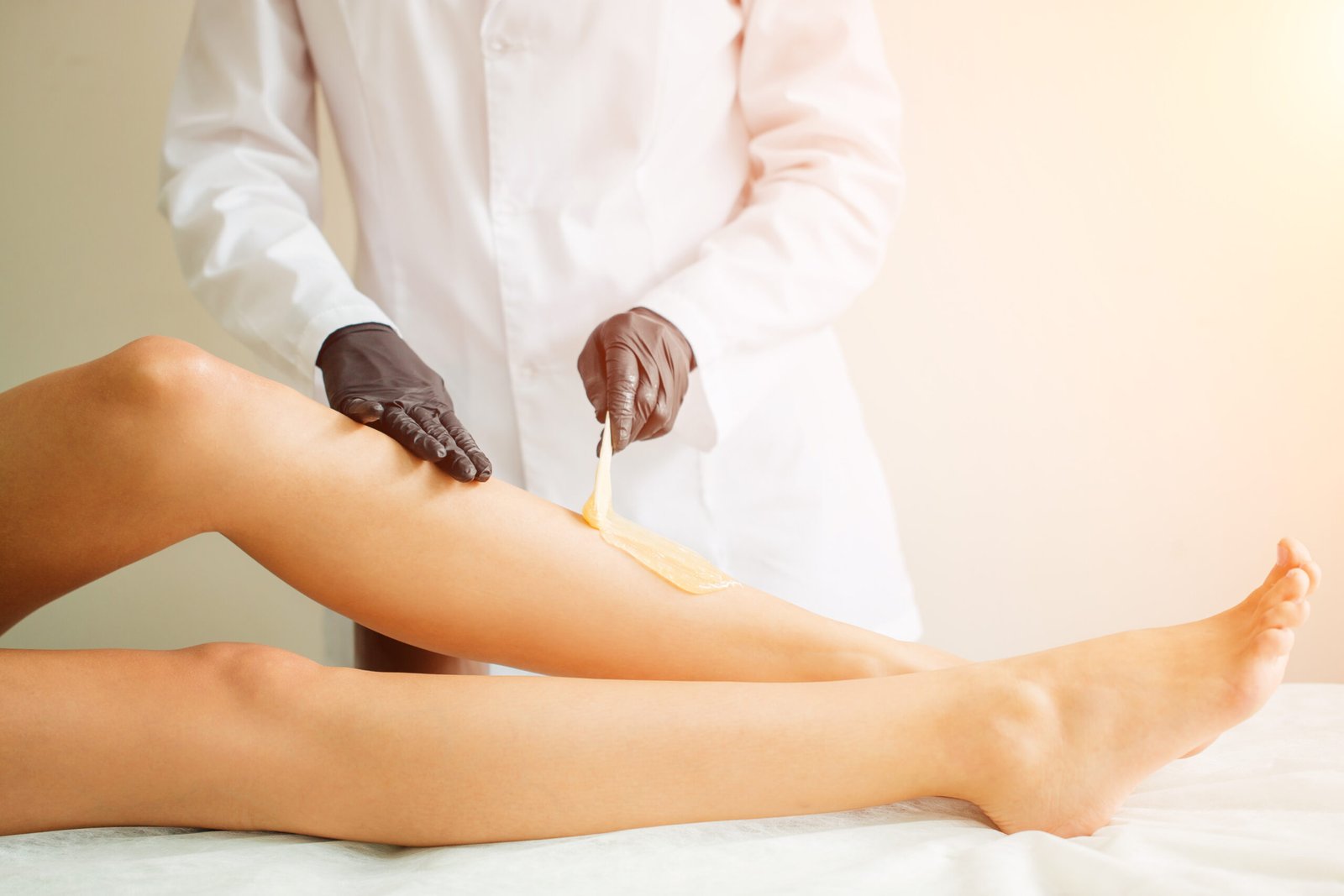 Close-up of a professional beautician waxing a client's legs at a spa, delivering sleek, smooth, and long-lasting hair removal results.