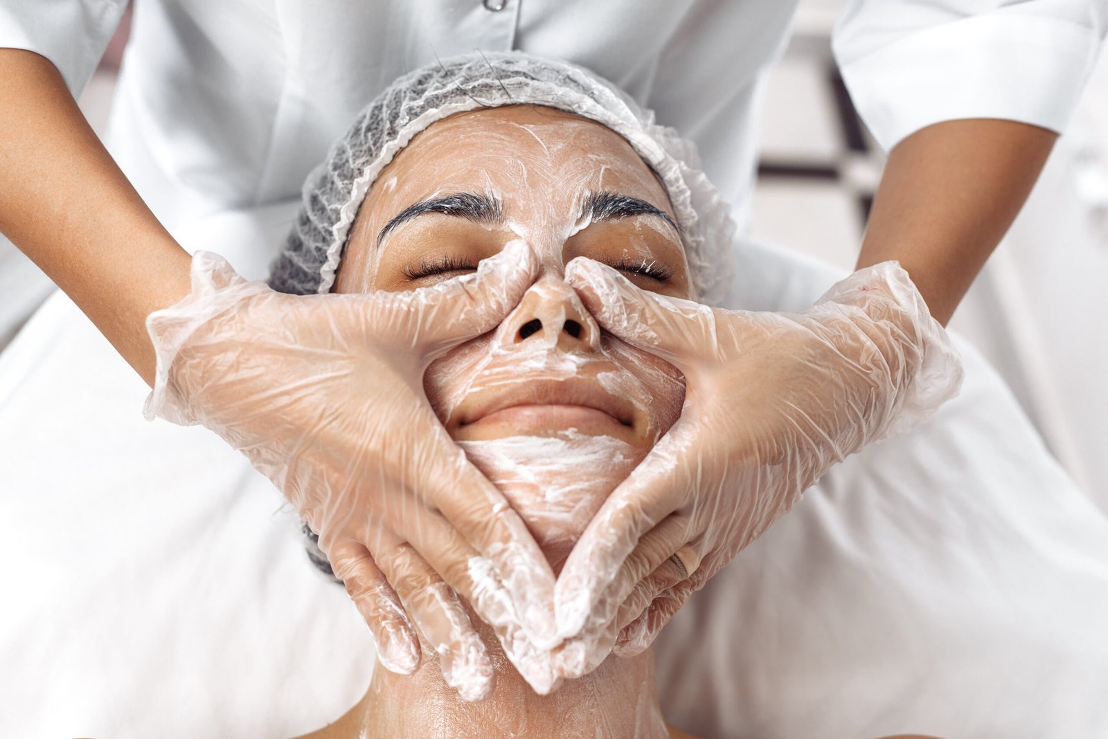 Professional cosmetologist applying cleansing cream during a Clean Up facial service for refreshed, polished, and meticulously groomed skin.