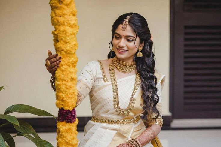A girl sitting near flowers with a very good bridal makeup done by coimbatore bridal makeup artist - Artysto Salon